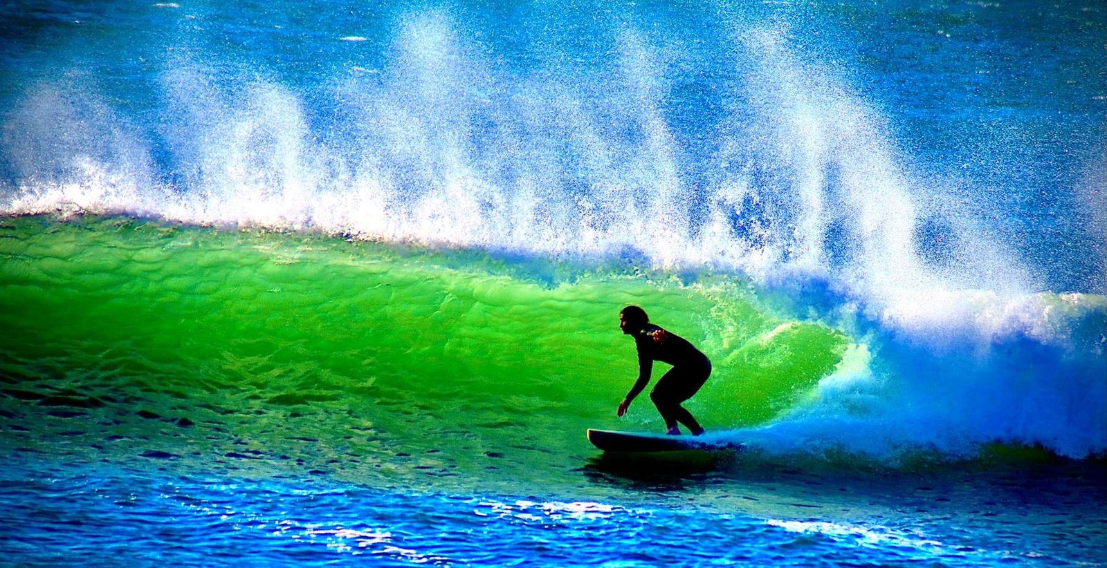Surfer dropping into a glowing green wave